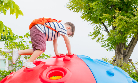 kid boy and backpack having fun to play on children's climbing toy at school playground,back to school outdoor activity.の写真素材