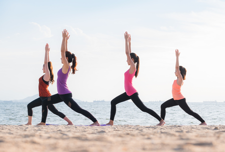 Yoga class at sea beach in evening ,Group of people doing Warrior poses with clam relax emotion at beach,Meditation pose,Wellness and Healthy balance lifestyleの写真素材