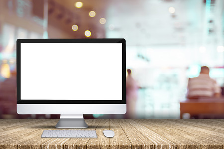 Blank screen desktop computer on plank wooden table top with blur restaurant bokeh background,Mock up for display or montage of designの写真素材