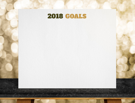 2018 goals on white paper poster on black marble table with gold bokeh lights at background,mock up...