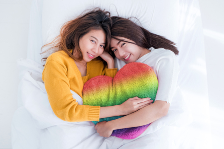 Asia lesbian LGBT Couple lay on bed and hug rainbow color pillow heart shape with happiness moment together,love win conceptの写真素材