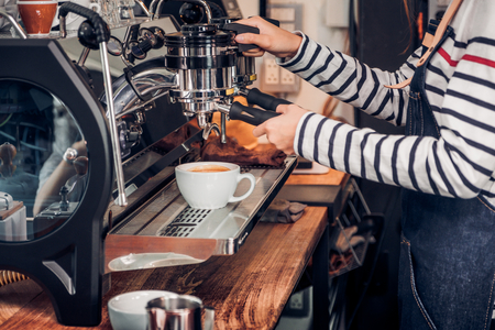 Close up woman barista making hot coffee with machine at counter bar in cafe restaurant,Food and drink service concept.の写真素材