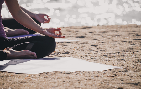 Close up hands of yoga master seated doing Hand Mudra and meditates on beach at coastline, Calm and relax concept,wellness and healthy lifestyleの写真素材