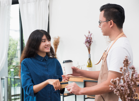 satisfied asia woman customer pay coffee drink with credit card to waiter barista,paid for to go coffee cup at coffee shop,Food and drink business,billing paymentの写真素材
