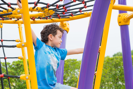 kid boy having fun to play on children's climbing toy at school playground,back to school...