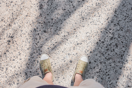 Aerial view of sneakers green canvas shoe with casual plants stand on grunge street with palm leaf shadow in sunny day at beach, Leave space on top for adding your text.の写真素材