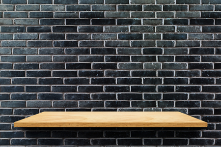 Empty wood board shelf at black brick wall background,Mock up for display or montage of product or design.の写真素材