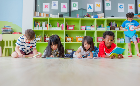 Group of diversity kid lay down on floor and reading tale book in preschool library,Kindergarten school education concept.の写真素材