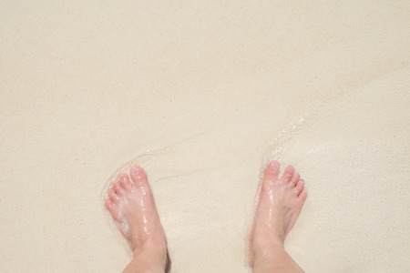 Top view barefoot standing on sand at sea beach at shore in sunny day,Relaxing in summer vacation travel time.copy space for adding textの写真素材