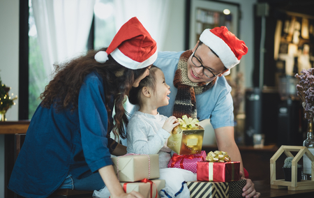 Happy family Asia family wear santa claus hat unwrap Christmas gift box at house xmas party,Holiday celebrating festive conceptの写真素材