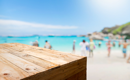 Empty wood plank table food stand with blur tourist on sand beach for summer vacation with bokeh light background,Template mock up for display or montage of productの写真素材