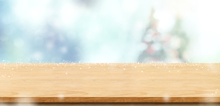 Empty wood board table top with abstract bokeh blur christmas tree and snow fall background with bokeh light,Holiday backdrop,Mock up banner for display or montage of product.の写真素材