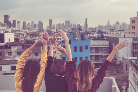Happy group of asia girl friends enjoy and arm up relax pose at roof top party at evening sunset,Holiday celebration festive,teenage lifestyle,freedom and funの写真素材
