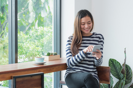 Happy Asia woman using mobile near window at cafe restaurant,Digital age casual lifestyle,life outside home conceptの写真素材