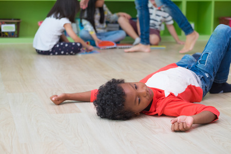 African American kid with loneliness emotion separate from group of friends in classroom in kindergarten preschool.bullying depression conceptの写真素材