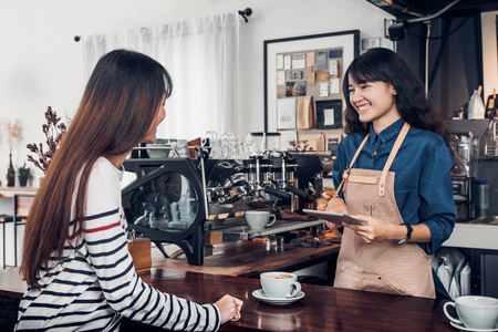 Asia Barista waiter take order from customer in coffee shop,cafe owner writing drink order at counter bar,Food and drink business concept,Service mind conceptの写真素材