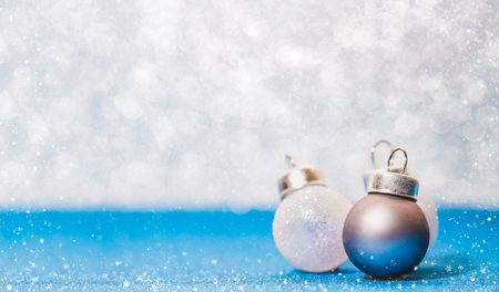 Christmas ball on vivid blue glitter floor and white bokeh blur wall with snow flake falling on ground.Banner with copy space for display of text or design.holiday festive celebration greeting cardの写真素材