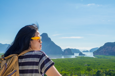 Happy young traveler woman backpacker looking at mountain with sea and enjoying a beautiful of nature at ,Freedom wanderlust,Khao Samed Nang Chee Viewpoint,Phang Nga,Thailandの写真素材