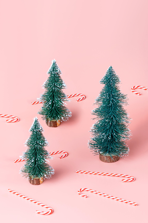Tree Christmas tree with candy cane on pastel pink studio background.Holiday festive celebration greeting card with copy spaceの写真素材