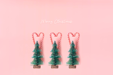Tree Christmas tree with candy cane hanging on pastel pink wall with white Merry christmas word.Holiday festive celebration greeting cardの写真素材