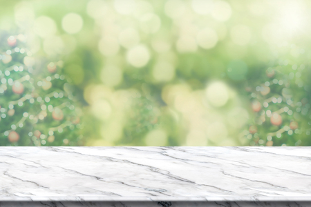 Empty white marble table top with abstract blur christmas tree background with bokeh light,Holiday backdrop,Mock up banner for display or montage of productの写真素材