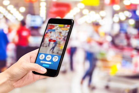 Hand hold mobile phone and using augmented reality ( AR ) app for see promotion sale in supermarket store,Digital lifestyle Technology conceptの写真素材