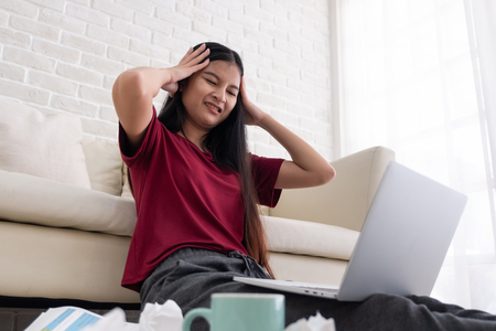 Asian woman freelancer stress emotion while working with laptop and paperwork at sofa in living room in house.work at home conceptの写真素材