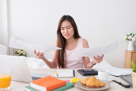 Asian woman freelancer upset with work problem with laptop on mess table.work at home concept.stress workingの写真素材