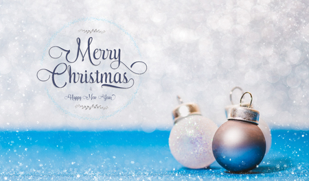 Merry Christmas and happy new year text and ball on vivid blue glitter floor and white bokeh blur wall with snow flake falling on ground.design holiday festive celebration greeting cardの写真素材