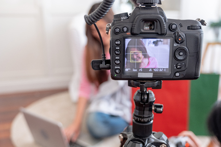 Asian young female blogger recording vlog video with review cloths T-shirt at home online influencer on social media concept.live streaming viral.focus on cameraの写真素材