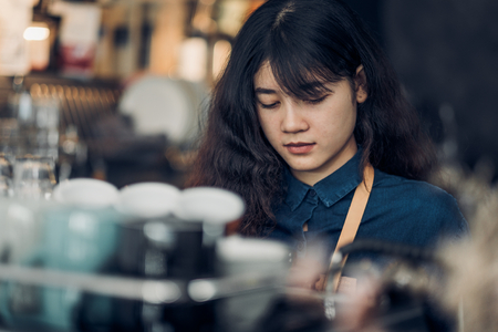 asian woman barista making hot coffee with machine at counter bar in cafe restaurant,Food and drink service conceptの写真素材