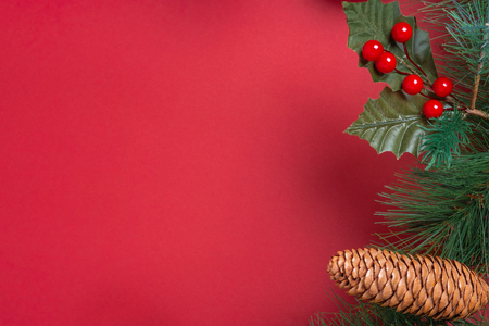 Christmas decoration and fir branches wreath with cherry and pine cone on red table background.の写真素材