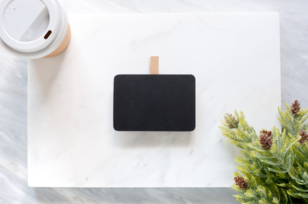 Top view of Clip blackboard,pine leaf and coffee cup on white marble block and stack on grey marble table.の写真素材