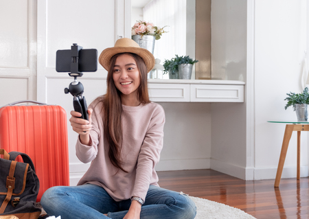 Asian young female blogger recording vlog video with mobile phone live streaming when travel.online influencer on social media viral concept