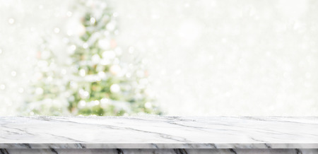White marble table top at blur bokeh christmas tree decor with string light background when show falling,Winter holiday greeting cardの写真素材