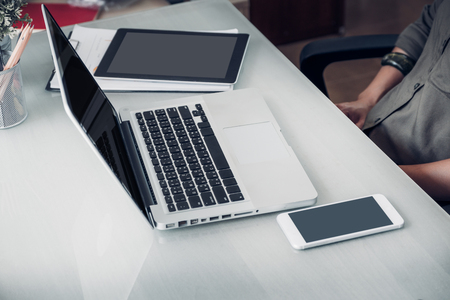 Close up laptop ,mobile phone and table on office desk in office with casual creative designer sitting at chair.clipping path screenの写真素材