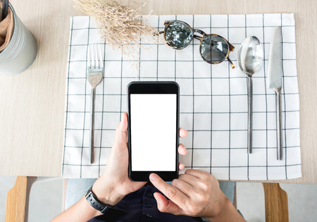 woman use mobile phone apps at restaurant table.Mobile payment.Digital leisure lifestyle.mock up template for display of content.top view angle.clipping path on screenの写真素材