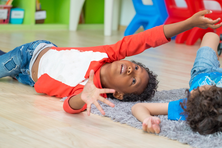 Two boy kid lying on floor and play together in preschool library,Kindergarten school education concept.diversity childrenの写真素材