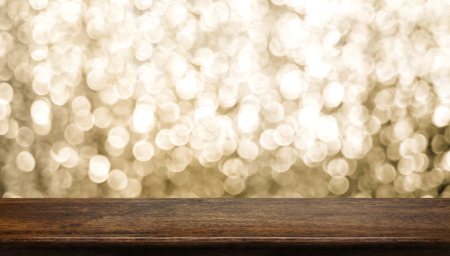 Empty old rustic dark wood table top with blur sparkling gold bokeh abstract background,panoramic banner for display or montage of product,Holiday seasonal concept backdropの写真素材