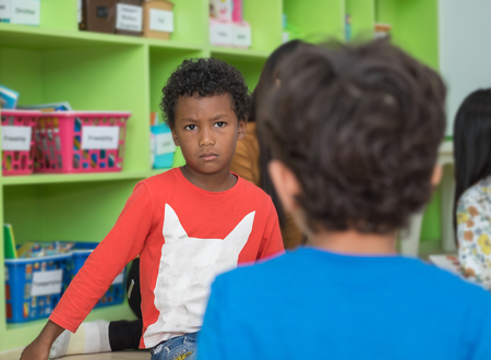 African american boy angry and looking at friend in school library in kindergarten.kids education conceptの写真素材