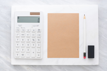 Top view of calculator, pencil, eraser and brown  notepad on white marble block and stack on grey marble table.Flat lay Mock up template for adding or display text or design.Stationery itemの写真素材