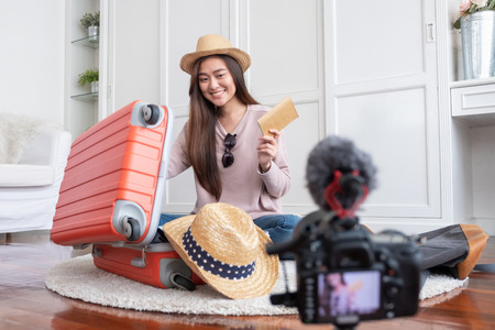 Asian young female blogger recording vlog video with vacation preparing to travel trip at home.online influcencer on social media conceptの写真素材