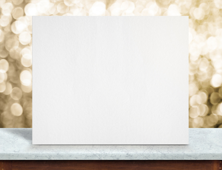 Blank white paper poster on white marble table top and sparkling gold bokeh light,Mock up to display or montage of your content,holiday backgroundの写真素材
