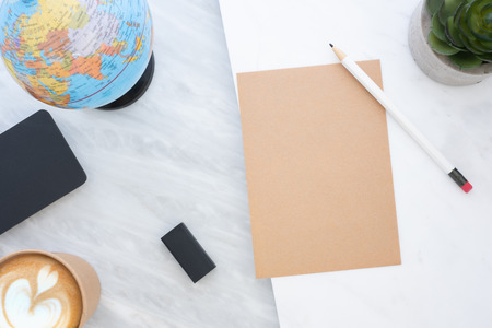 Top view of white pencil on brown paper with blue globe,blackboard,coffee cup and plant on marble table.new yearâs resolutions concept.ecology.mock up for adding textの写真素材
