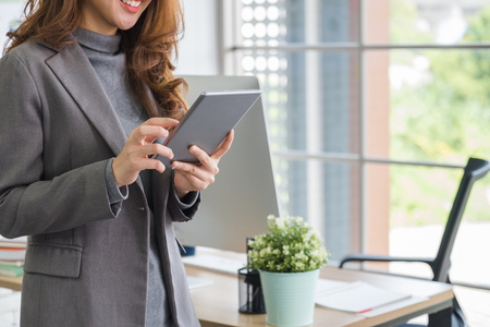 Businesswoman standing with smile face using tablet at modern office.Digital business lifestyle conceptの写真素材