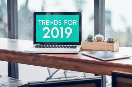 Trends for 2019 word in laptop computer screen with tablet on wood stood table in at window with blur background,Digital Business or marketing trendingの写真素材