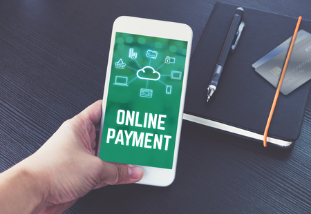 Hand holding mobile talking with online payment on screen with black notebook and credit card on black wooden desk,Digital marketing technology conceptの写真素材