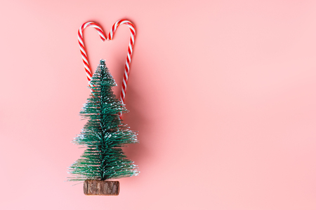Christmas tree with candy cane hanging on pastel pink wall.Holiday festive celebration greeting cardの写真素材