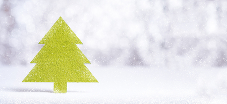 Close up Merry Christmas word on green Christmas tree with sparkling red star with snow fall on white floor at silver background bokeh light,Banner mock up for winter holiday seasonal greeting cardの写真素材