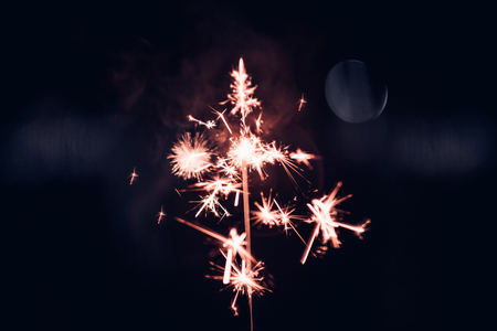 Hand holding burning Sparkler blast on a black background at night,holiday celebration event party,dark vintage toneの写真素材
